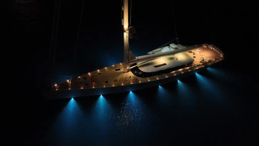 Vista aérea nocturna de un yate iluminado en aguas oscuras